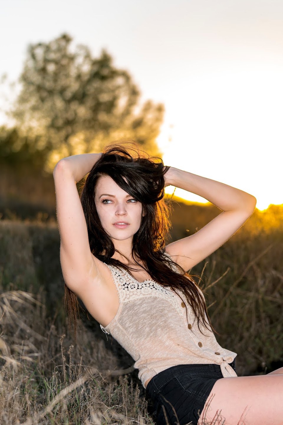 Brooke reclining in dry grass with warm sunlight behind her
