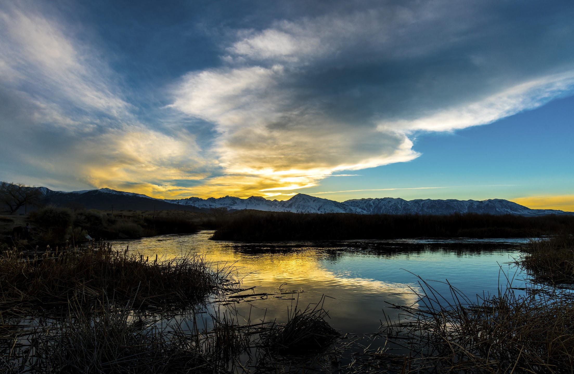 Warm sunset beneath dramatic clouds reflected in a still lake