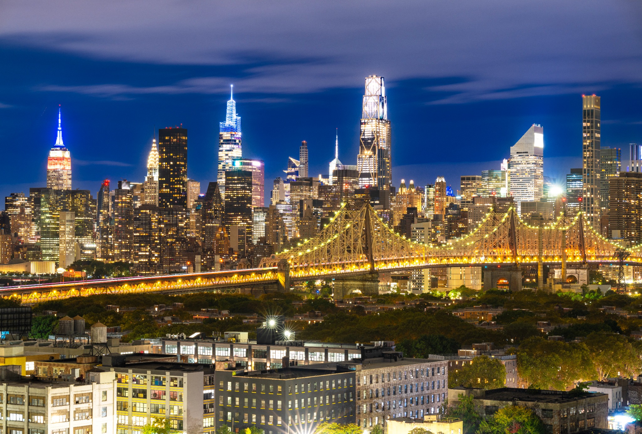 New York City skyline glowing at blue hour above the Queensboro Bridge